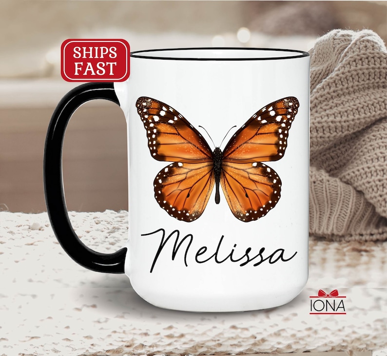 May include: White ceramic coffee mug with a black handle and rim. The mug features a colorful butterfly illustration and the name "Melissa" in black cursive writing.