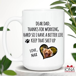 May include: White ceramic coffee mug with a black paw print and the text "Dear Dad, Thanks for working hard so I have a better life. Keep that shit up. Love, Max". A photo of a dog is in a heart shape on the mug.