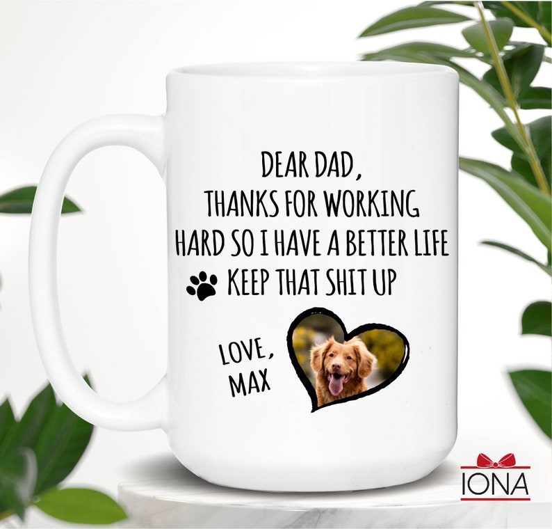 May include: White ceramic coffee mug with a black paw print and the text "Dear Dad, Thanks for working hard so I have a better life. Keep that shit up. Love, Max". A photo of a dog is in a heart shape on the mug.