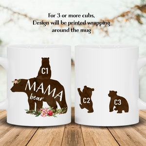 May include: White ceramic mug with a brown silhouette of a mama bear and three cubs. The mama bear has the text "MAMA bear" on her back. The cubs are numbered C1, C2, and C3. The mug has a floral design at the bottom.