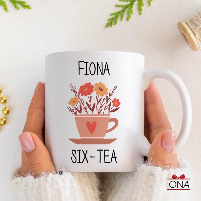 May include: White ceramic mug with a floral design and the text "Fiona Six-Tea".