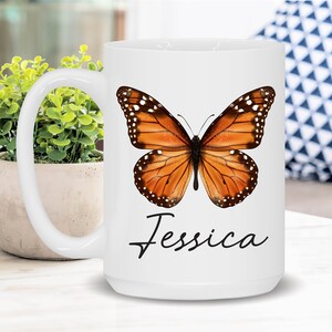 May include: White ceramic mug with a butterfly design and the name "Jessica" printed on the front. The butterfly is orange and black with white spots.