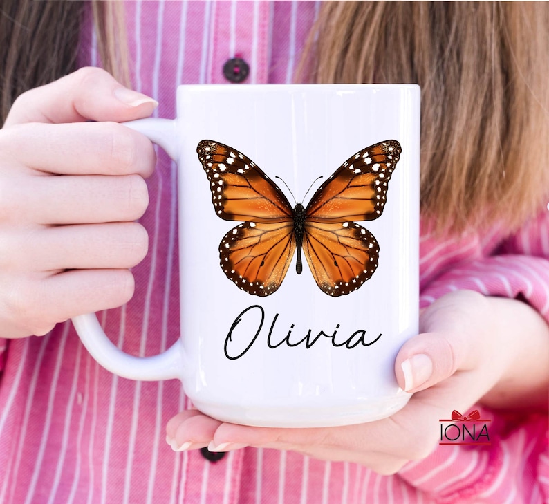 May include: White ceramic mug with a brown and orange butterfly graphic and the name "Olivia" written in black cursive.