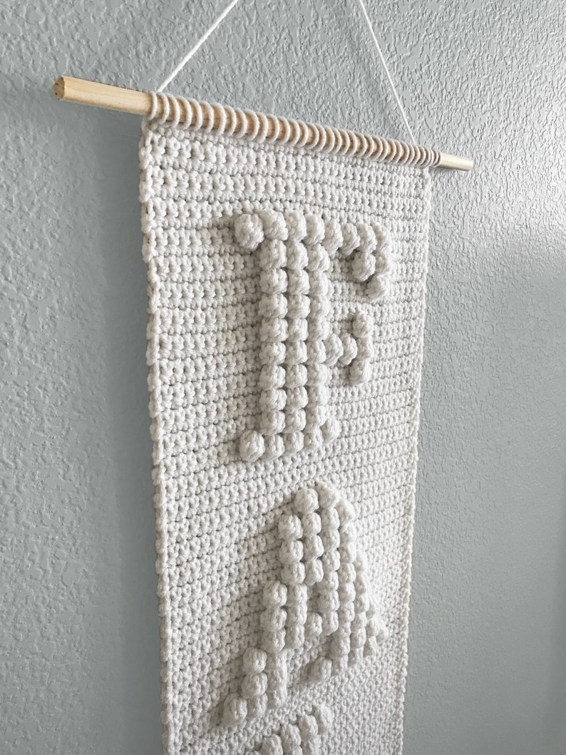 May include: A white crocheted wall hanging with the word "Peace" spelled out in raised stitches.