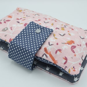 May include: A pink and blue fabric diaper changing pad with a white polka dot pattern on the flap. The flap has a silver snap closure.