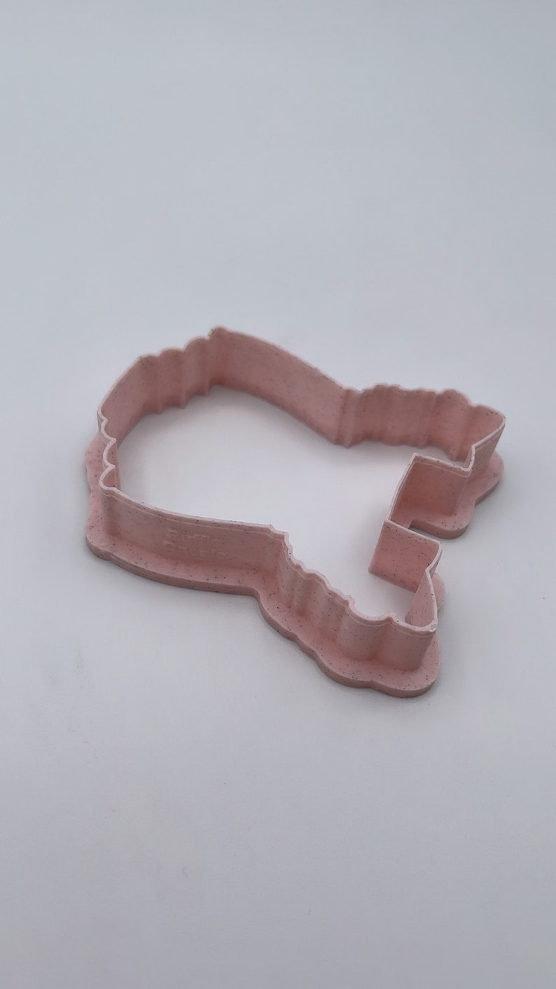 Peut inclure: Un emporte-pi&egrave;ce en plastique rose en forme de fant&ocirc;me de dessin anim&eacute;. L'emporte-pi&egrave;ce a un design d&eacute;taill&eacute; avec un bord ondul&eacute; et un petit trou en haut.