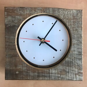 May include: A rustic wooden clock with a white face and black hands. The clock is framed in a square piece of reclaimed wood.