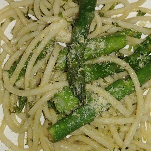 May include: A plate of spaghetti with asparagus and parmesan cheese. The spaghetti is cooked al dente and the asparagus is tender-crisp. The parmesan cheese is grated and sprinkled over the top.