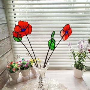 set of flowers and poppy buds made of transparent orange stained glass