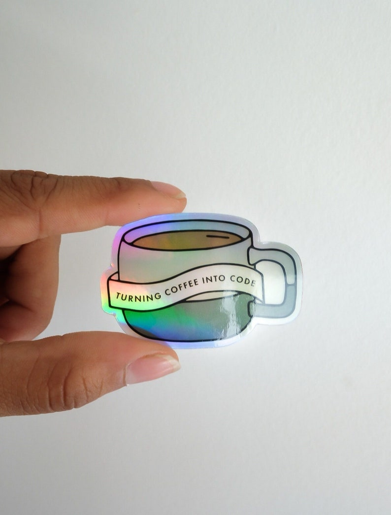 May include: A holographic sticker of a coffee mug with the text "Turning coffee into code" on a banner.