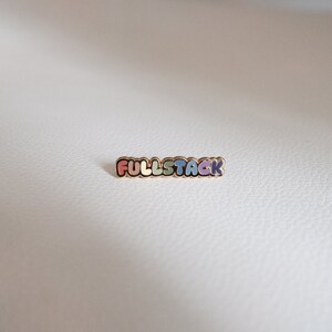 May include: A gold-colored pin with the word "FULLSTACK" in rainbow colors.