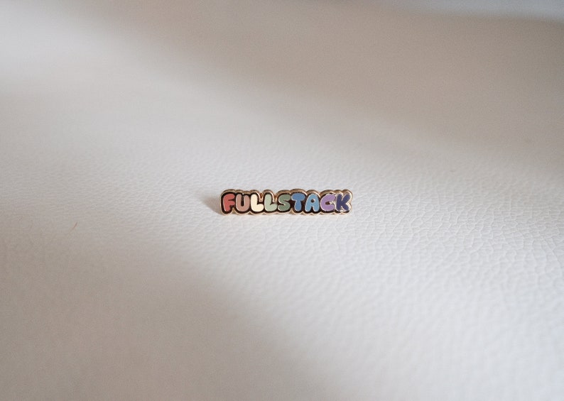 May include: A gold-colored pin with the word "FULLSTACK" in rainbow colors.