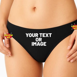Könnte beinhalten: Schwarzer Slip mit dem weißen Text "YOUR TEXT OR IMAGE". Der niedrig geschnittene Slip hat auf jeder Seite ein Logo. Das Thema ist anpassbare Kleidung.