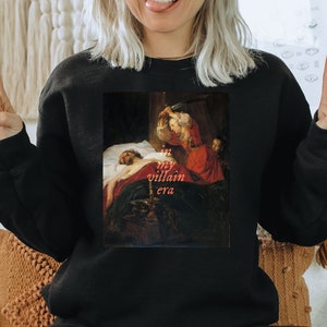 A black book lover sweatshirt featuring a painting of a woman and a sword with the text 'in my villain era'. The perfect bookish gift.