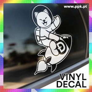 Könnte beinhalten: Weißer Vinyl-Aufkleber mit einem Cartoon-Hund, der einen Raumanzug trägt und auf einer Rakete mit einem Bitcoin-Symbol reitet. Der Aufkleber befindet sich auf einem Autofenster. Der Text "VINYL DECAL" befindet sich unter dem Bild. Die Website-Adresse "www.ppk.pt" befindet sich in der oberen rechten Ecke.