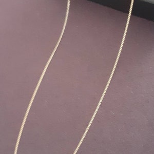 May include: A gold chain necklace on a purple background.