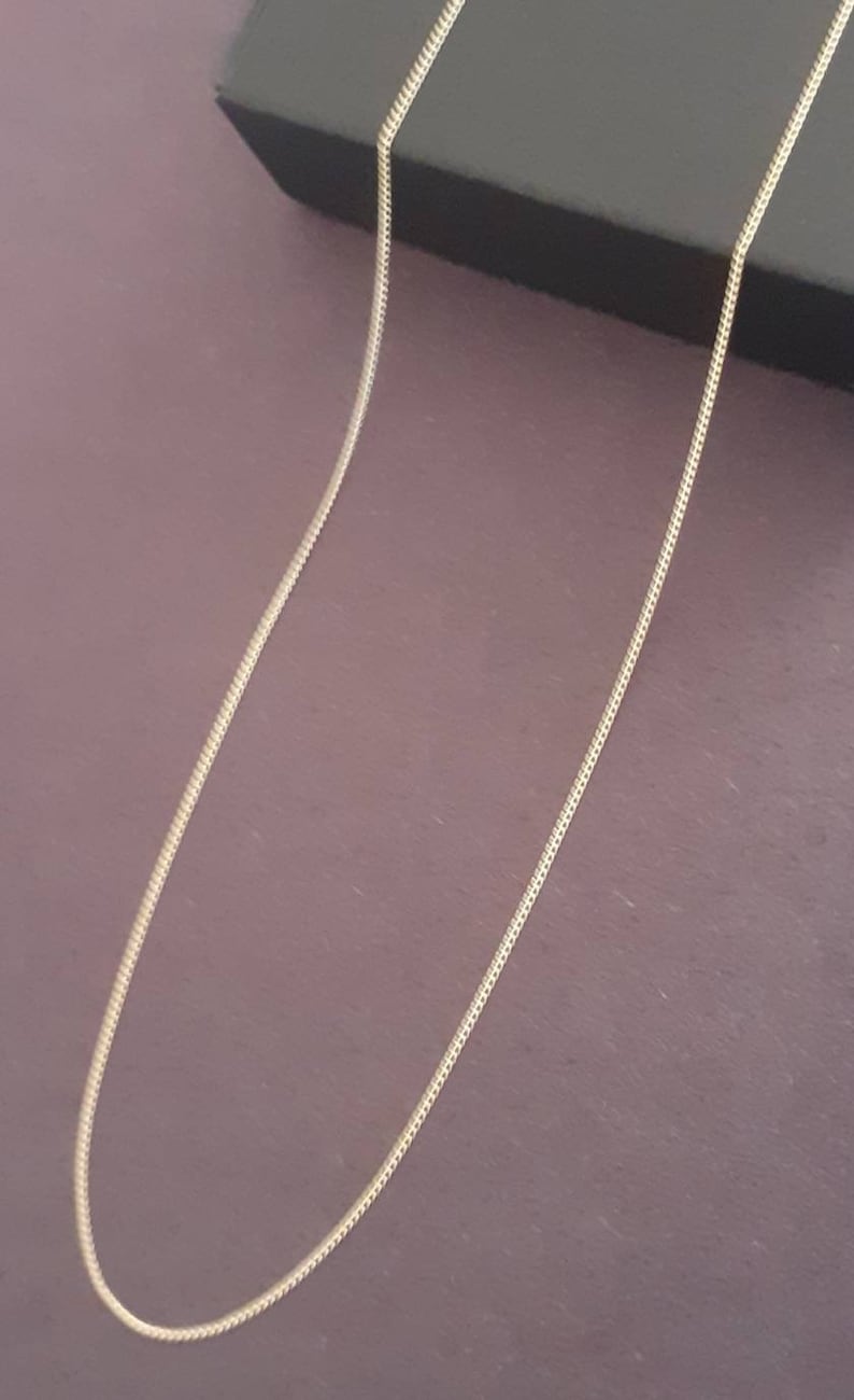 May include: A gold chain necklace on a purple background.