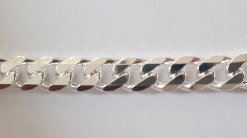 Op de afbeelding: Een zilveren curb-ketting met een platte, gepolijste afwerking.