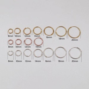 May include: A set of 10 gold and silver hoop earrings in various sizes, ranging from 8mm to 20mm. The earrings are arranged in three rows, with the smallest earrings at the top and the largest earrings at the bottom.