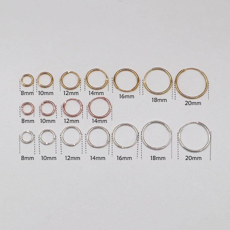 May include: A set of 10 gold and silver hoop earrings in various sizes, ranging from 8mm to 20mm. The earrings are arranged in three rows, with the smallest earrings at the top and the largest earrings at the bottom.