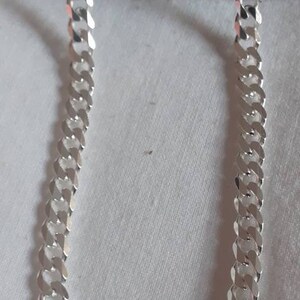 Op de afbeelding: Een zilveren curb-ketting met een dik, plat schakeld ontwerp.