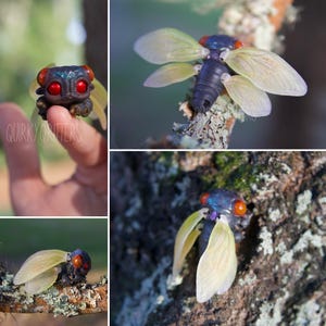 Puede incluir: Un primer plano de una figurita de cigarra hecha a mano con alas iridiscentes azules y negras, ojos rojos y un cuerpo detallado. La figurita está posada en una rama con un fondo verde.