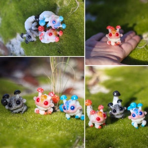May include: Five small, hand-painted, resin figurines of fantastical creatures with mushroom-like growths on their heads. The creatures are in various colours, including white, grey, blue, and red. The figurines are posed on a bed of green moss.