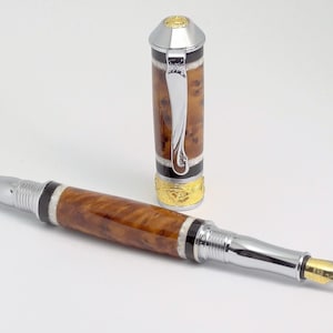 May include: A brown and silver fountain pen with a decorative cap. The pen has a gold-colored band and a black and white stripe pattern.
