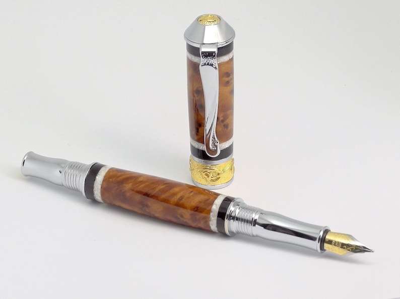 May include: A brown and silver fountain pen with a decorative cap. The pen has a gold-colored band and a black and white stripe pattern.