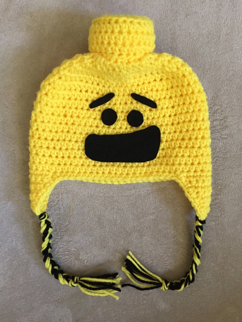 May include: Yellow crocheted hat with a black smiling face and black and yellow braided ties.