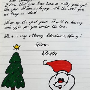 以下が含まれることがあります： サンタクロースからルーシーへの手書きの手紙。メリークリスマスを願い、学校での頑張りを励ましています。手紙は緑のクリスマスツリーと赤いサンタクロースの顔で飾られています。