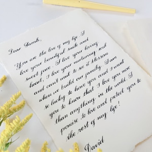 May include: A handwritten love letter on a white paper background with yellow flowers in the foreground. The letter reads, "Dear Sarah, You are the love of my life. I love your beautiful smile and sweet face. I love your loving heart, I love your nurturing soul and can't wait to see it blossom when we build our family. I am so lucky to have you and I want you to know that I love you more than anything in the world. I promise to love and protect you to the rest of my life! David"