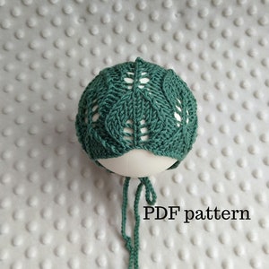 May include: A green knitted baby hat with a leaf pattern. The hat has a tie at the bottom. The text "PDF pattern" is visible below the hat.