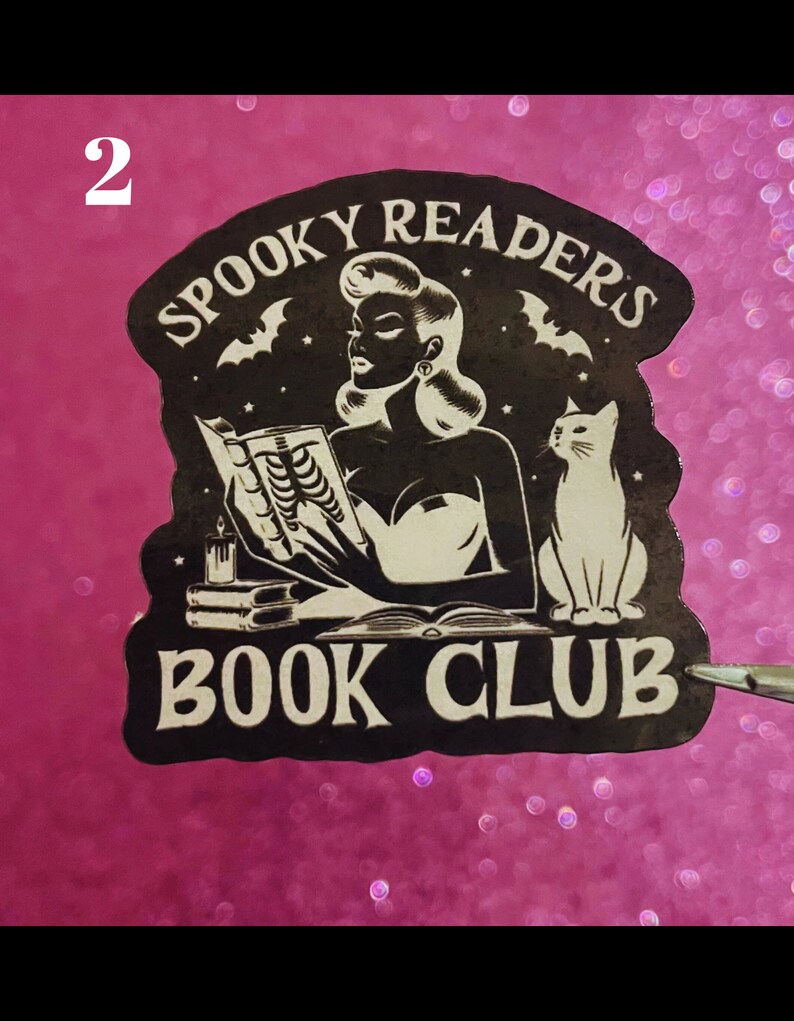 May include: Black and white sticker with a woman reading a book, a cat, and bats. The text reads "Spooky Readers Book Club".