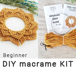 Op de afbeelding: Een DIY macramé-kit voor beginners met een gele koord, een knoop-gids en een voltooid voorbeeld van een stervormige macramé-wandhanger. De kit bevat instructies voor het patroon "Sun Mandala".