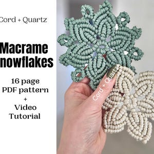 Puede incluir: Se muestran dos copos de nieve de macramé, uno verde claro y otro beige. Los copos de nieve se sostienen en una mano. La imagen incluye el texto "Cord + Quartz" y "Macrame Snowflakes".