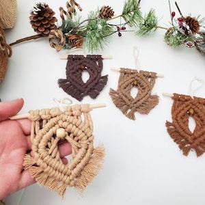 May include: Four macrame wall hangings with wooden dowels and wooden beads. The wall hangings are in various shades of brown, including light brown, medium brown, and dark brown.