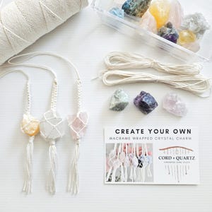 May include: Create your own macrame wrapped crystal charm kit. The kit includes three crystals, white macrame cord, and instructions. The crystals are a yellow citrine, a clear quartz, and a pink rose quartz.