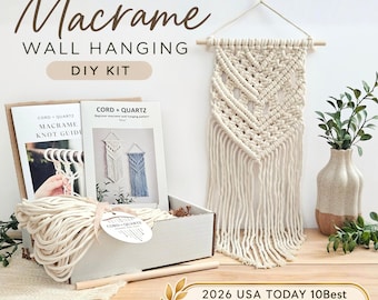 May include: A macrame wall hanging DIY kit featuring a white cotton cord, a wooden dowel, and instructional guides labeled CORD + QUARTZ. The kit includes a finished macrame wall hanging with a chevron pattern and fringe, plus a box.