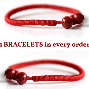 May include: Two red cord bracelets, each featuring a section of tightly wrapped thread and two round red beads with small black speckles. The text 2 BRACELETS in every order! is centered between the two bracelets, which are shown in a horizontal orientation.