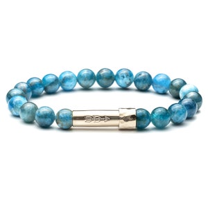 Peut inclure: Un bracelet en pierres bleues avec un charme en argent en forme de flèche. Le bracelet est composé de perles rondes et possède un fermoir en argent martelé.