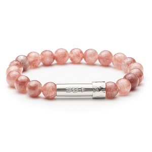 May include: A pink gemstone bracelet with a silver clasp featuring an arrow design. The bracelet is made of round beads.