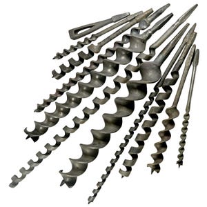 Puede incluir: Colección de brocas de barrena antiguas, dispuestas sobre un fondo blanco. Las brocas de metal oscuro presentan un diseño en espiral para perforar agujeros. La colección incluye brocas de varios tamaños y formas, mostrando su artesanía histórica. La imagen muestra las herramientas desde varios ángulos.