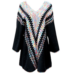 Pode incluir: Túnica preta com decote em V e mangas compridas. A túnica apresenta um padrão em zigue-zague colorido na gola e na parte superior do peito, com tons de arco-íris de rosa, azul, amarelo e verde. As mangas e a bainha têm uma borda a condizer.