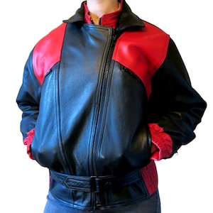 May include: Black and red leather jacket with a zip-up front, a collar, and a belt at the waist. The jacket has red shoulder panels and red lining visible at the cuffs. The jacket is a classic style.