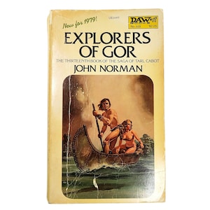 May include: Vintage paperback book titled "Explorers of Gor" by John Norman. The cover art features a couple in a boat on water. The book is from 1979 and has a price tag of $2.25. The book is part of the "DAW Books" series.
