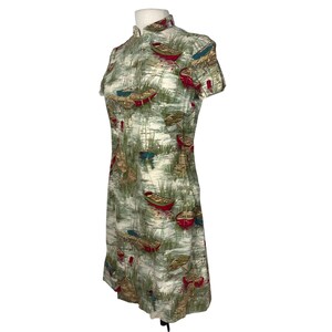 May include: A vintage-style dress with a mandarin collar and short sleeves. The dress features a print of boats on a lake with green, red, and blue accents. The dress is knee-length and made of a lightweight fabric.