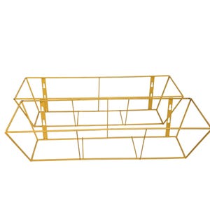 May include: Two gold-coloured metal wall-mounted storage baskets. The baskets have a geometric design with a rectangular shape and triangular ends. Each basket has mounting brackets for easy installation. The baskets are empty.