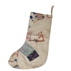 May include: A quilted Christmas stocking with a patchwork design. The stocking features a variety of fabric patterns, including stripes, floral prints, and geometric shapes, in shades of blue, pink, and green. It has a loop for hanging.