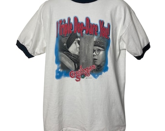May include: White t-shirt with a black ringer, featuring a photo of two boys from the film "A Christmas Story" with the text "I Triple Dog-Dare You!" printed on the front.